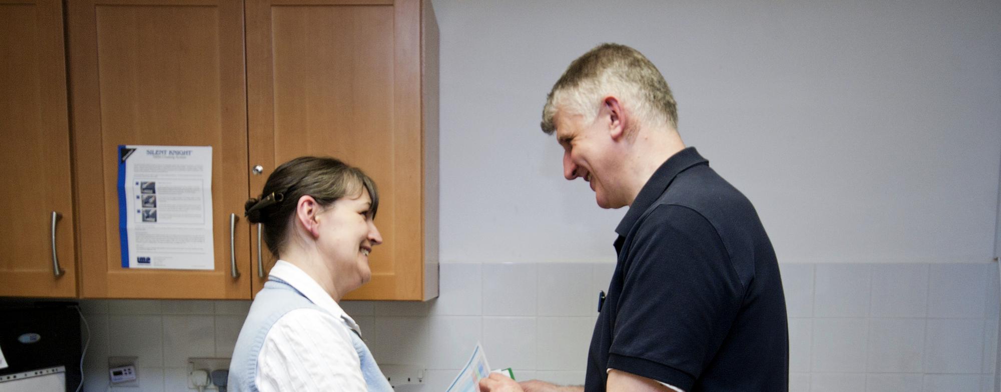 Two people, a man and a woman, talking to each other in an indoor setting. 