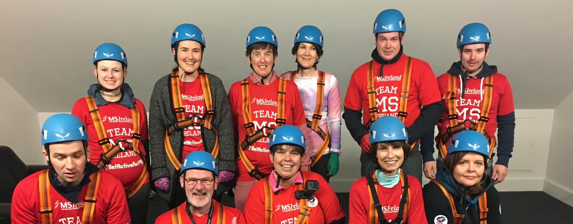 A large group of people, all wearing red t-shirts and helmets, preparing to abseil for MS Ireland