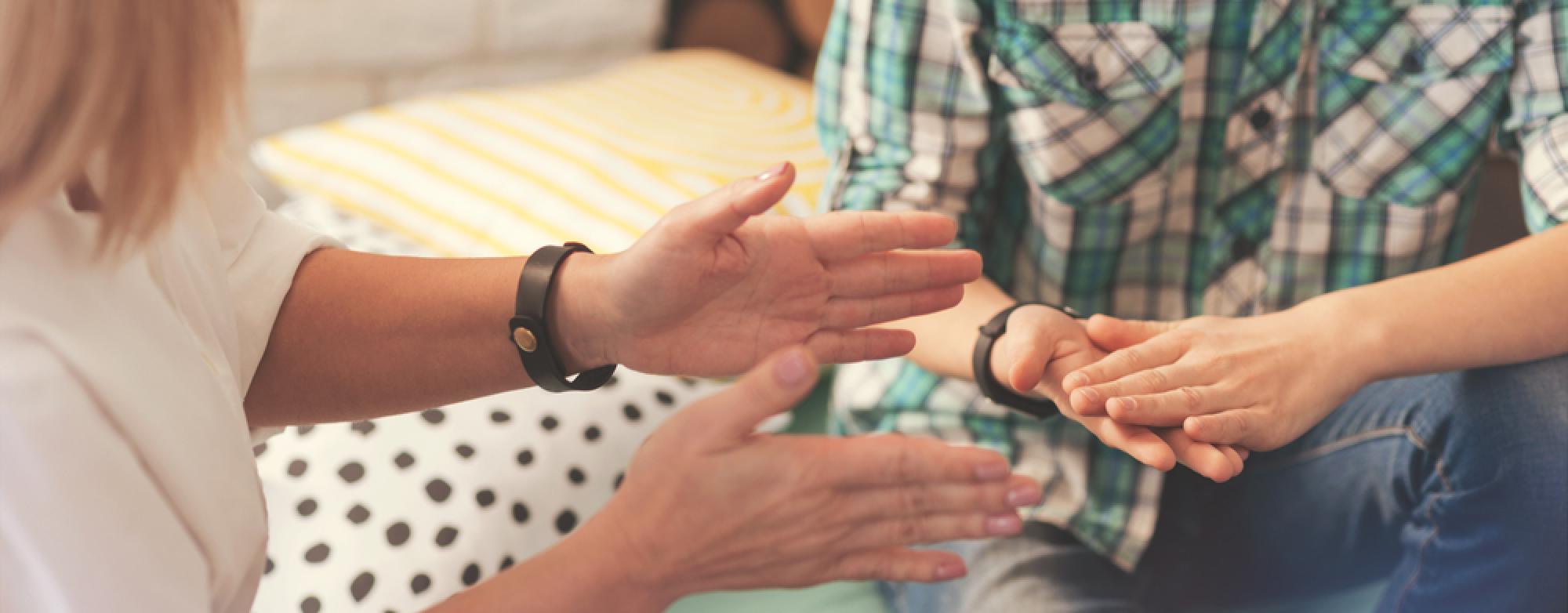 Two individuals sitting and using hand gestures.