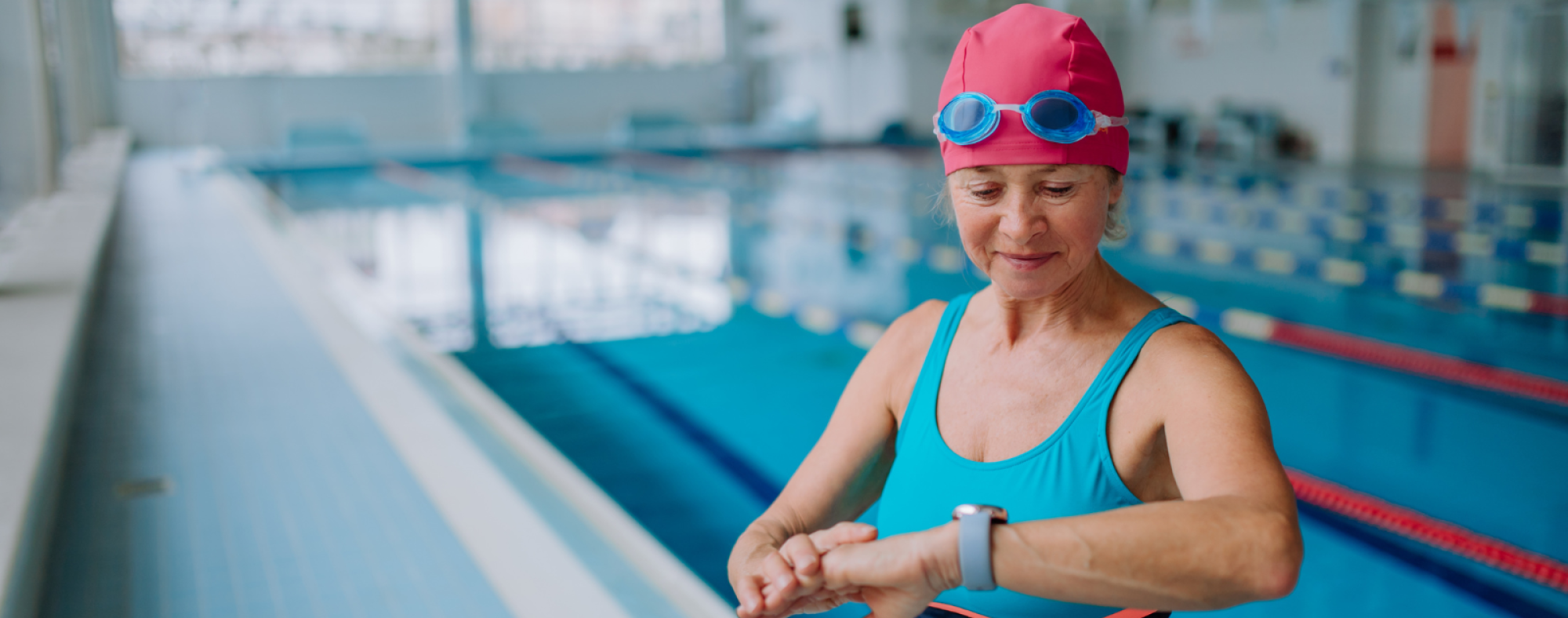 Swimmer checking time with wristwatch beside a swimming pool.