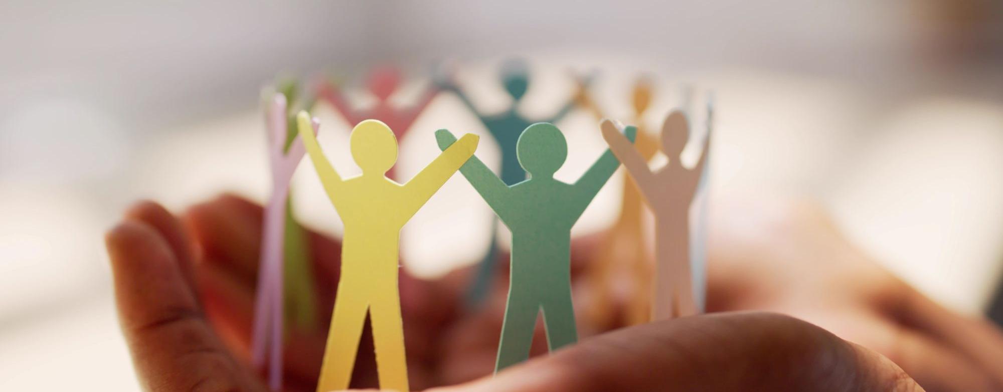 Paper people figures in a circle held in hands.