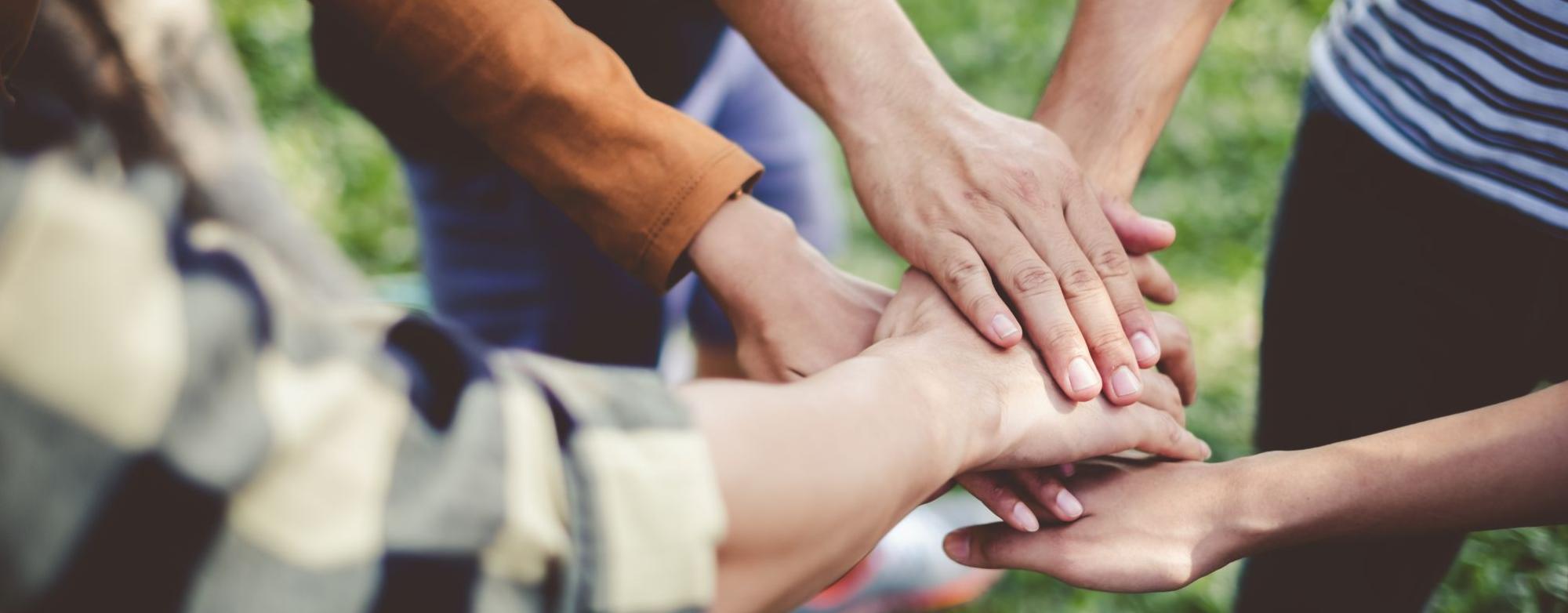 A group of people with their hands stacked together outdoors