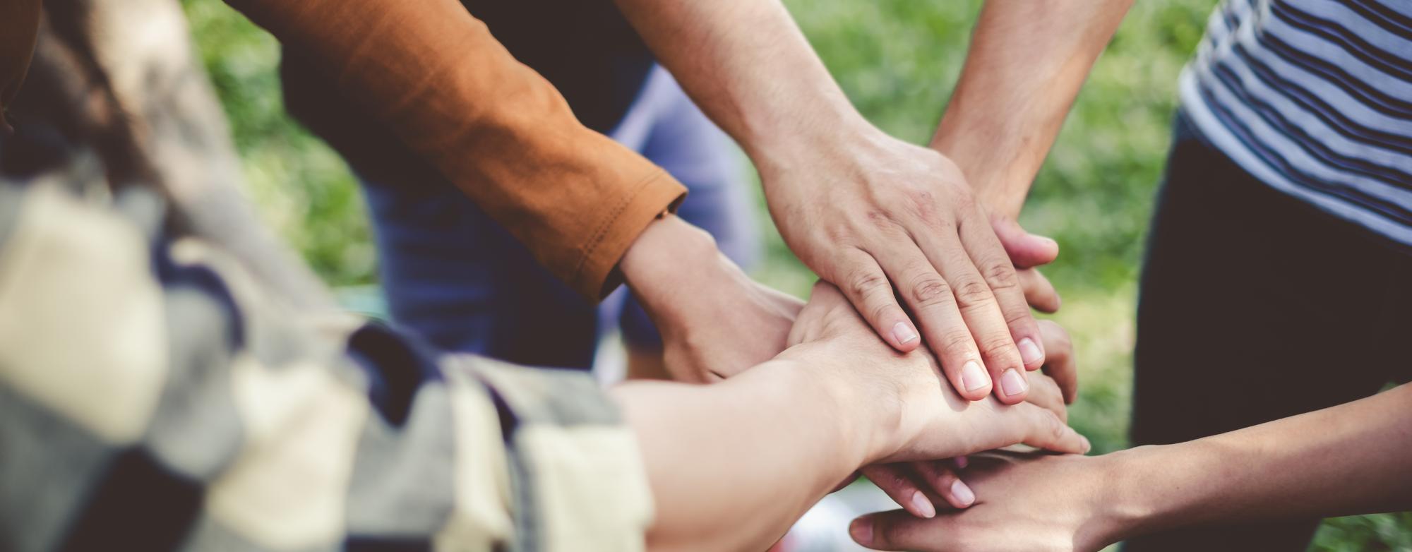 Volunteers placing their hands together in a show of teamwork and support.