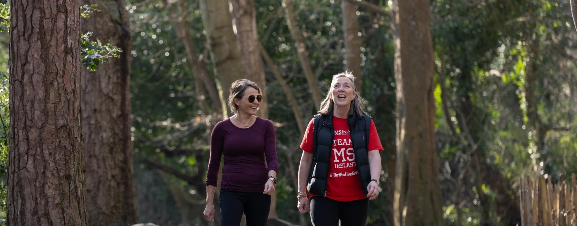Two people walking and smiling together along a wooded park path during a STEPtember fundraising event.