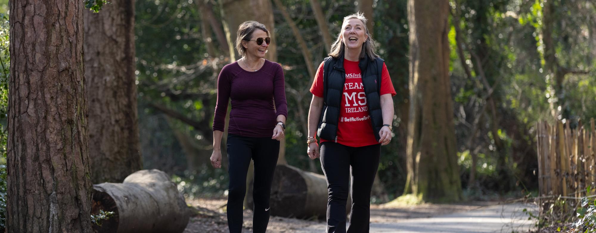 Two people walking and smiling together along a wooded park path during a STEPtember fundraising event.
