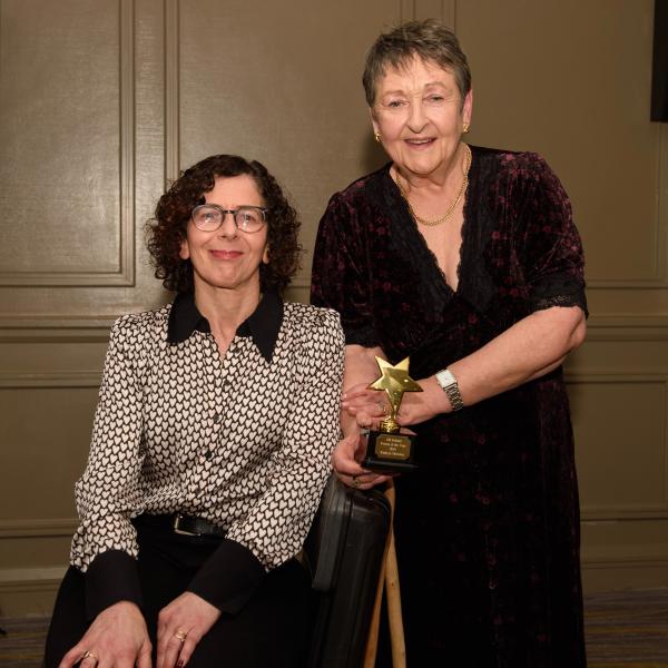 Kathryn, MS Ireland Person of the Year 2024, standing beside the seated MS Ireland Chairperson, both smiling.