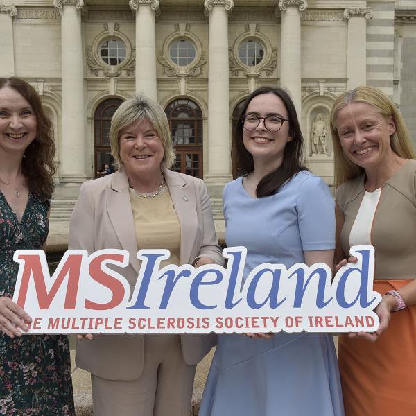 Representatives of the PROMISE Research Project stand outside a government building holding an MS Ireland sign.