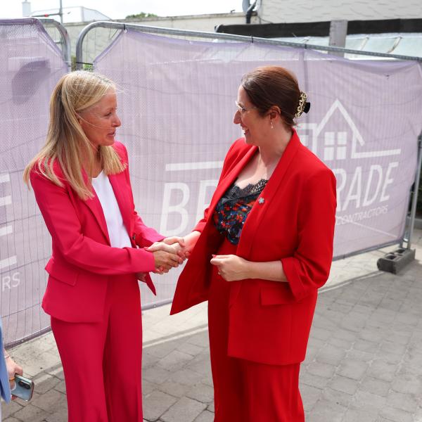 Two women shaking hands at an MS Ireland Care Centre event in 2026 while another attendee looks on.