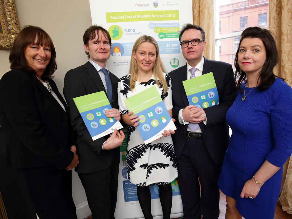 Five people standing together, each holding a copy of the new 'Societal Cost of MS' booklet