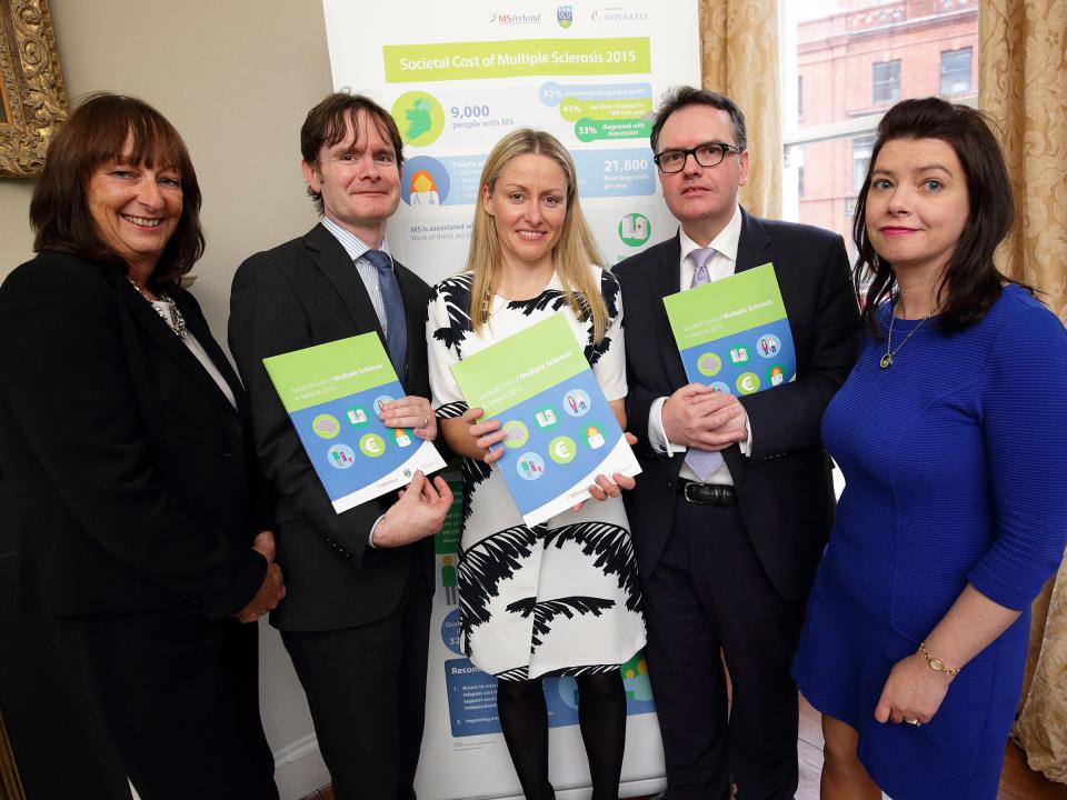 Five people standing together, each holding a copy of the new 'Societal Cost of MS' booklet