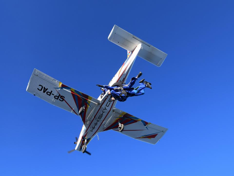 A small plane flying against a clear blue sky, with no clouds in sight