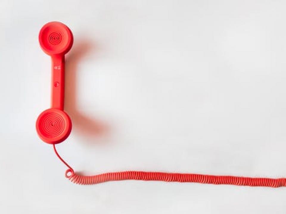 Red phone with cord on a white background. 