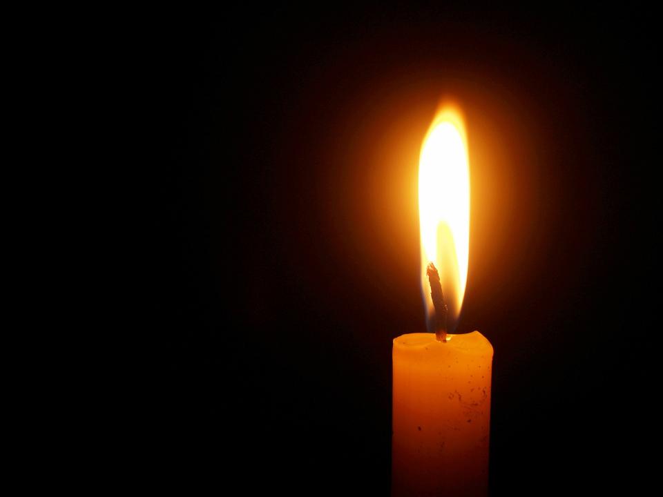 Close-up of a candle with a gently flickering flame, glowing softly.