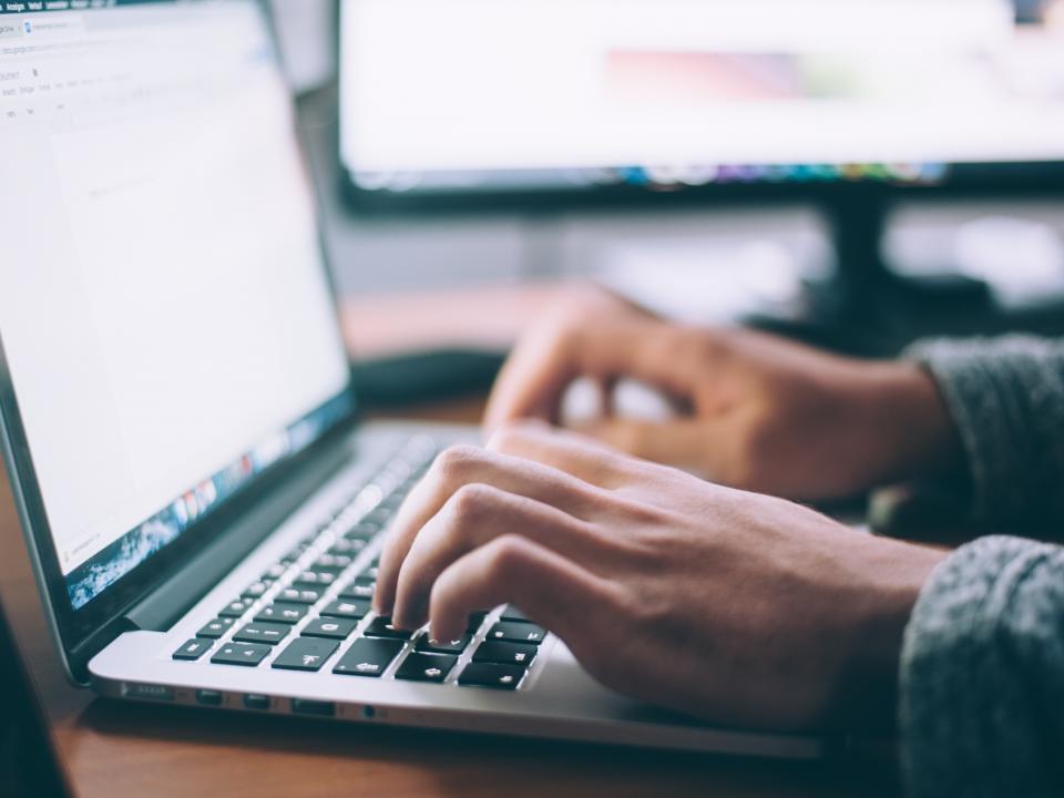 Close-up of a person's hands typing on a laptop keyboard