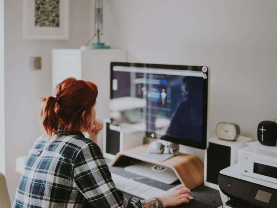 Person sitting at a desk, looking at a computer screen