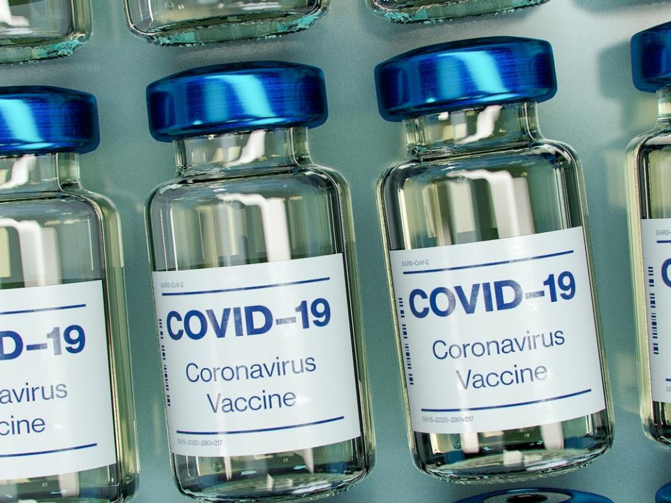 Glass vials with blue lids and white cabled with blue text stating 'COVID-19'