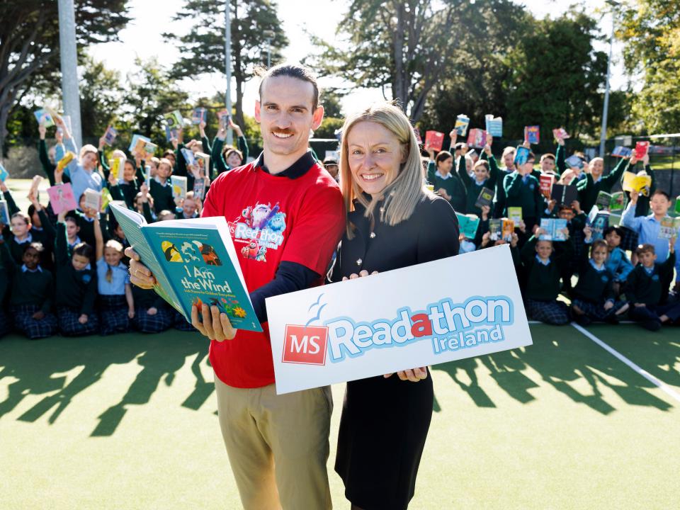 MS Readathon Ireland launch event with children holding books and two people in front holding a book and event sign
