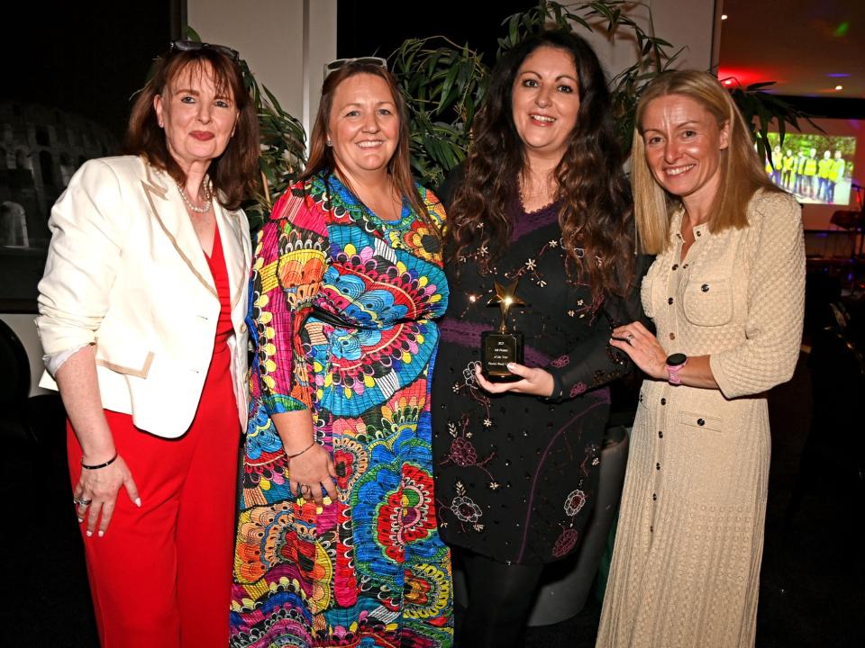 Four people standing together at the MS Ireland Annual Awards 2025 gala dinner, with the award winner holding a trophy