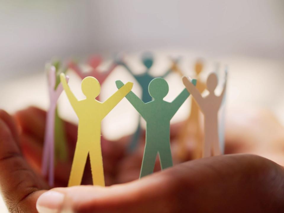 Paper people figures in a circle held in hands.