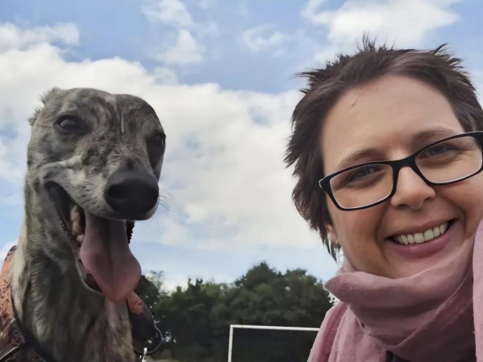 Willeke smiling outdoors with her whippet Oisín