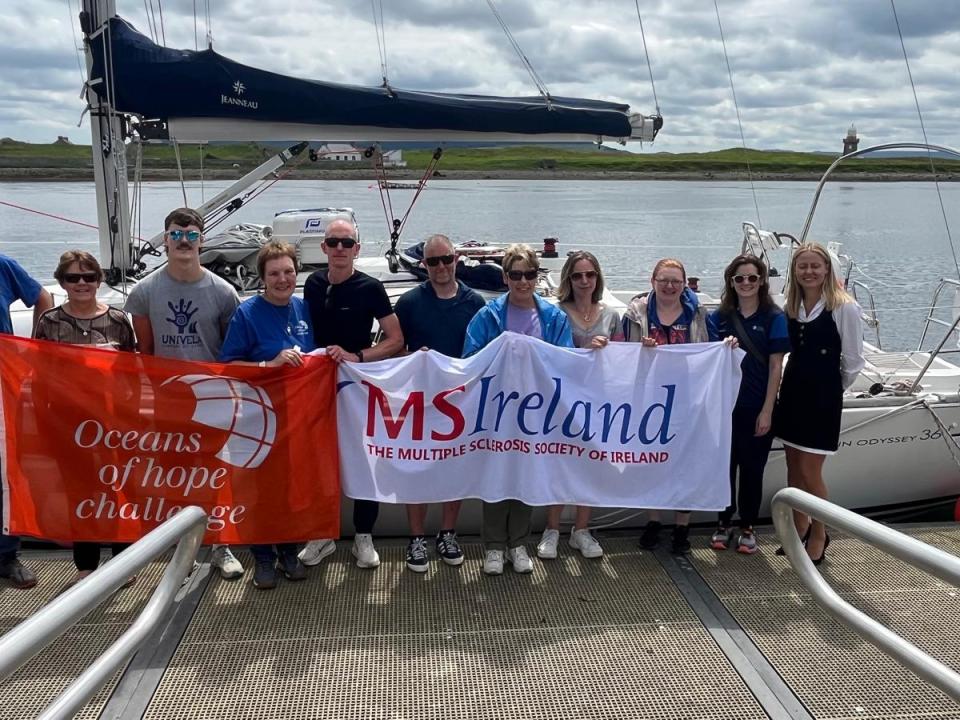 Group holding MS Ireland and Oceans of Hope banners in front of a sailing boat.