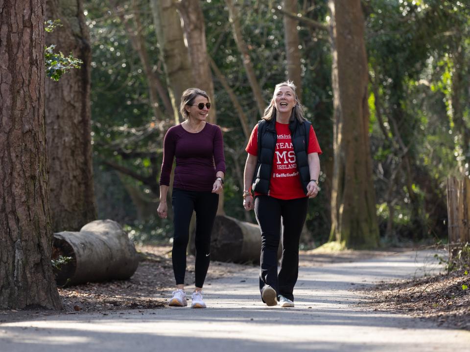 Two people walking and smiling together along a wooded park path during a STEPtember fundraising event.