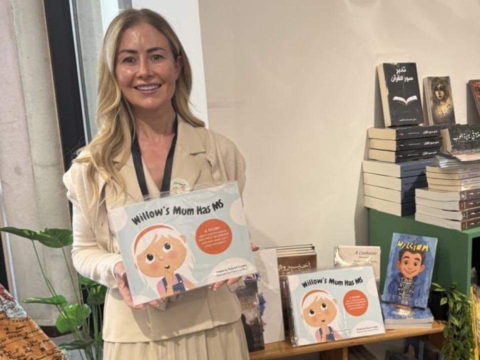 Deborah Cuddihy holding her children's book Willow’s Mum Has MS