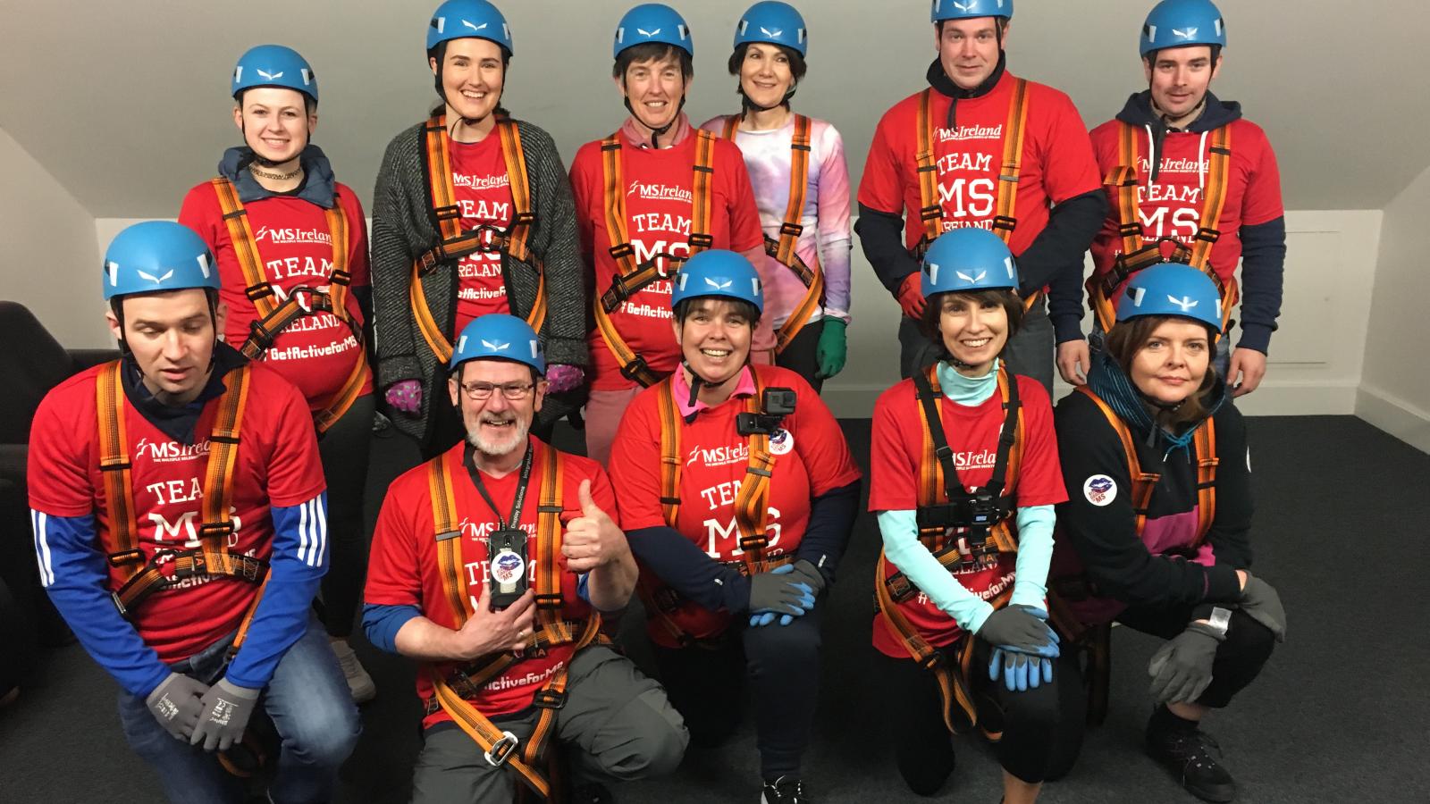 A large group of people, all wearing red t-shirts and helmets, preparing to abseil for MS Ireland