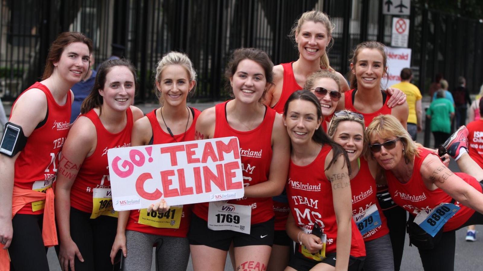 A group of happy participants in red MS Ireland t-shirts, gearing up for the race, with one group holding a sign.