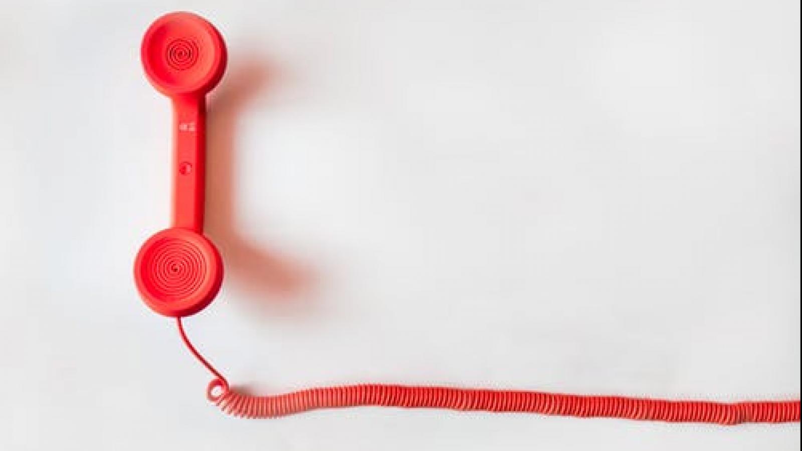 Red phone with cord on a white background.