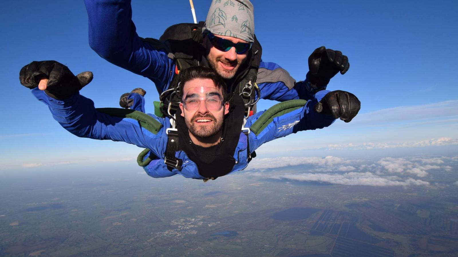 Two people freefalling through the sky, with a clear blue background.