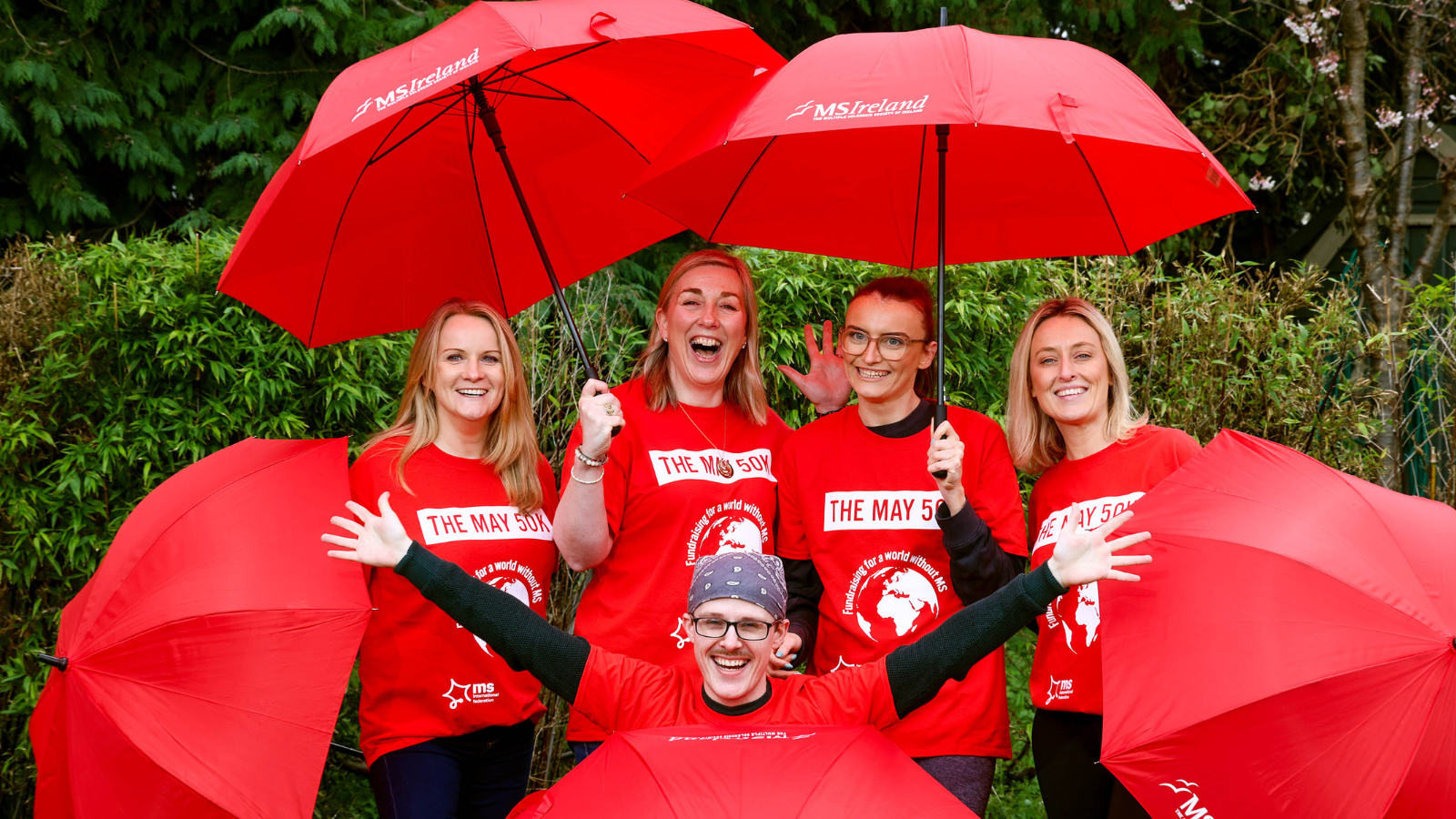 Group of people in red t-shirt holding red umbrellas 