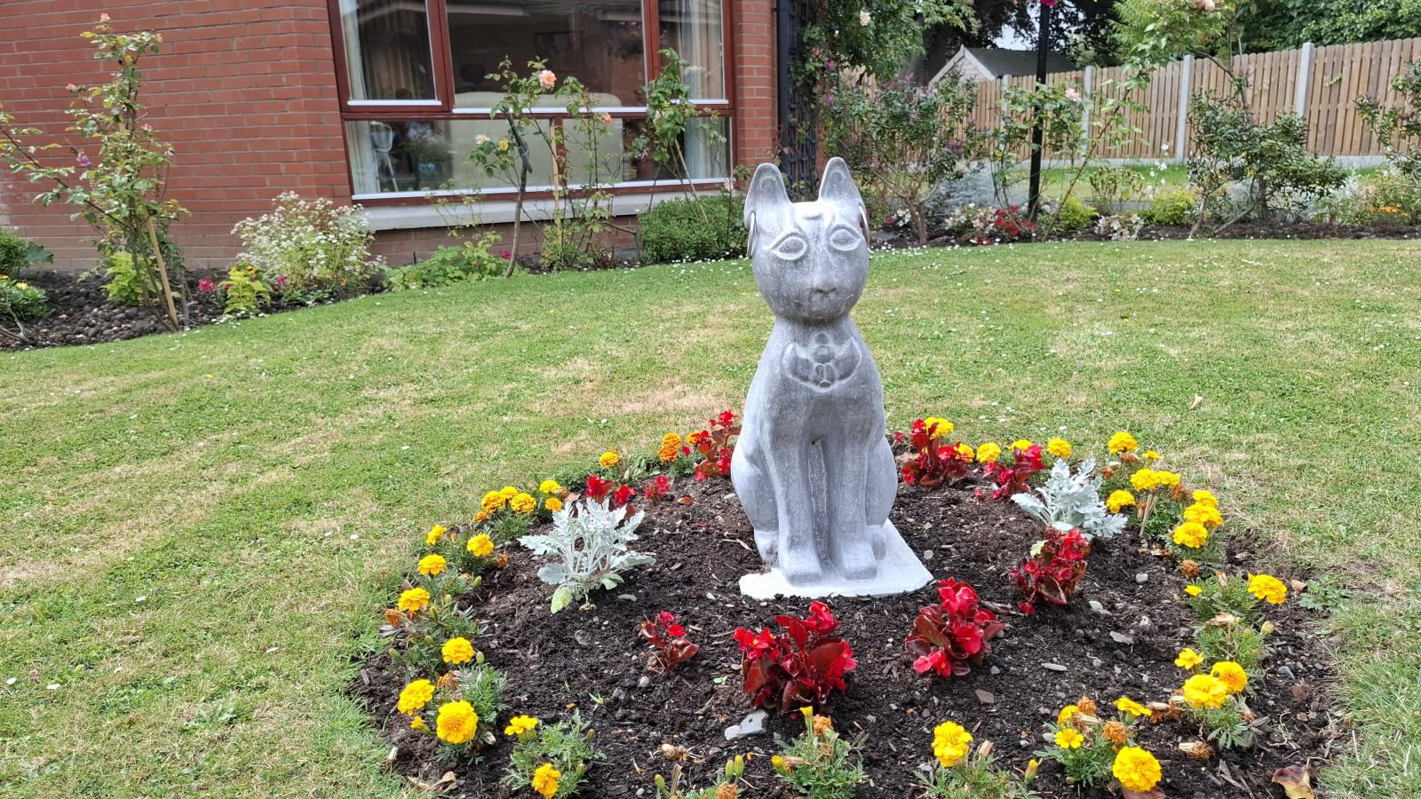 Handcrafted sculpture surrounded by colourful flowers in the MS Care Centre garden, donated by Wheatfield Prison