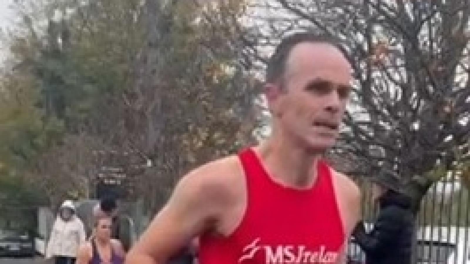 A runner wearing an MS Ireland vest during a road race, with other participants behind him