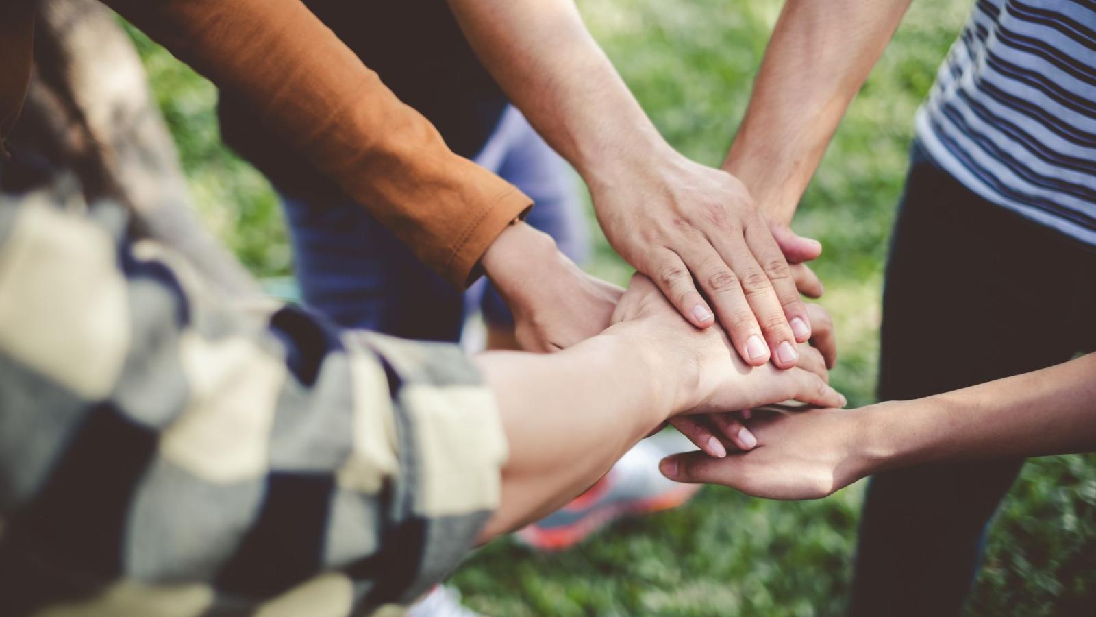 A group of people with their hands stacked together outdoors