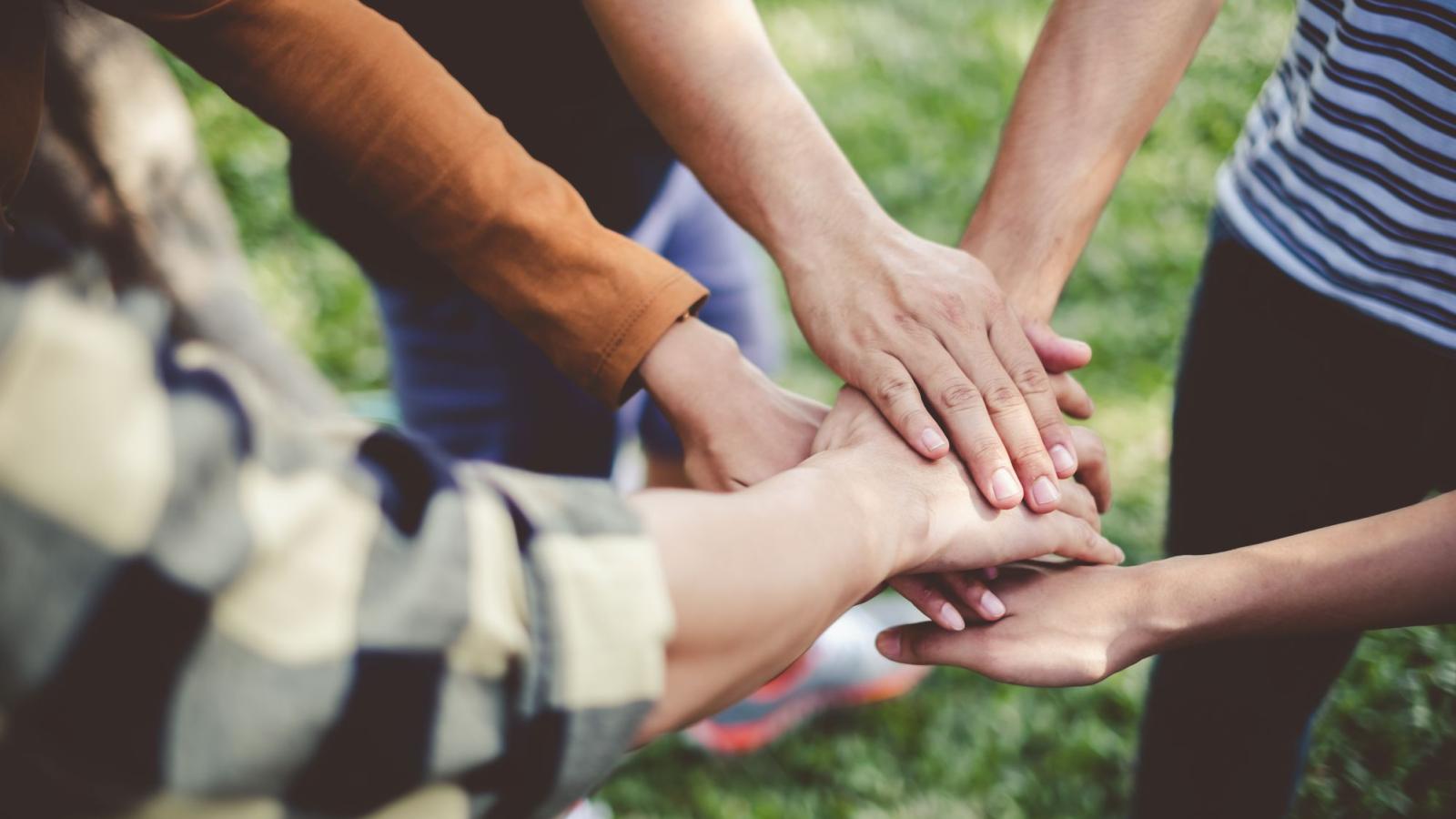 A group of people with their hands stacked together outdoors